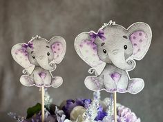 there are two cupcake toppers with an elephant on them and flowers in the background