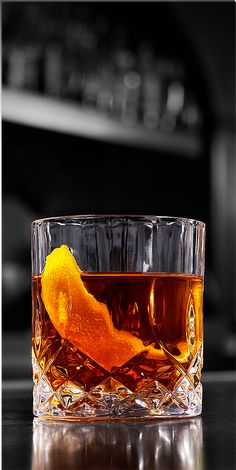 a glass filled with an orange peel on top of a table