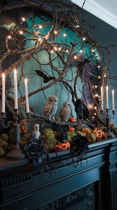 an ornate mantle with candles, fake owls and pumpkins