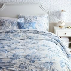 a bed with blue and white comforters in a bedroom next to a night stand