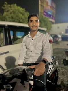 a man riding on the back of a motorcycle next to a white van at night