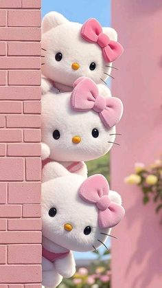 two hello kitty stuffed animals hanging from the side of a brick wall with pink flowers in the background