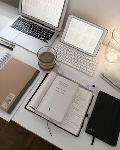 an open laptop computer sitting on top of a desk next to a notebook and pen