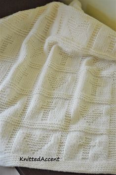 a white knitted blanket sitting on top of a bed