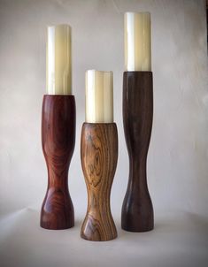 three wooden candlesticks sitting next to each other on top of a white surface