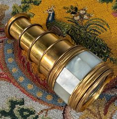 an antique brass and glass telescope on a colorful rug with a peacock in the background