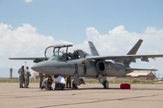 an air force jet sitting on top of an airport tarmac with people standing around it