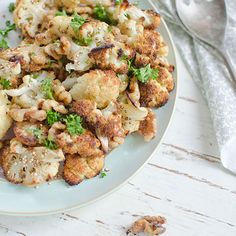 a white plate topped with cauliflower and broccoli next to a fork