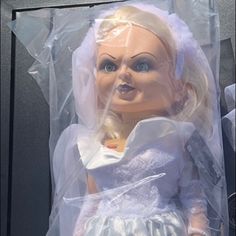 the doll is wearing a white dress and veil, but it's still in its packaging