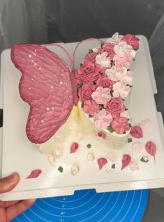 a cake decorated with pink and white flowers on top of a blue plate in the shape of a butterfly