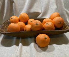 a wooden box filled with oranges sitting on top of a white cloth covered table