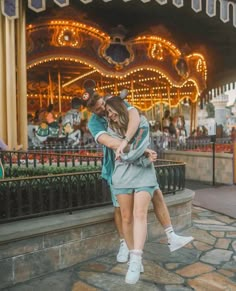 a man and woman are hugging in front of a merry - go - round ride