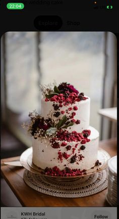 a three tiered white cake with red flowers and greenery on the top layer