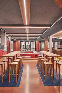 an empty restaurant with tables and stools in the center, along with blue tiles on the floor