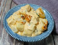 a blue plate topped with chicken covered in gravy on top of a wooden table