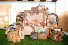 a table filled with lots of different items on top of a grass covered field next to a window