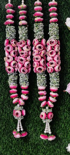 pink and white flowers are arranged in rows on the grass with pearls hanging from them