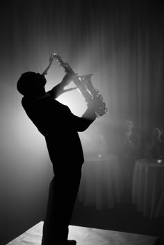 a man standing in front of a table holding a saxophone