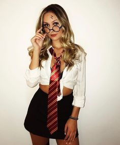 a woman wearing glasses and a tie poses for the camera with her hand on her eyeglasses