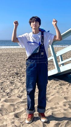 a young man standing on top of a sandy beach