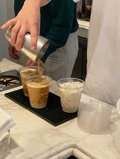 a person pouring something into a cup on top of a counter