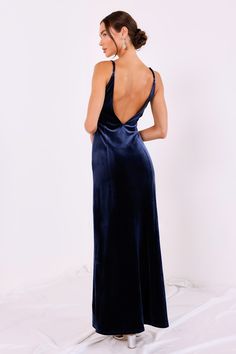 the back of a woman wearing a blue velvet evening gown with spaghetti straps and open shoulders