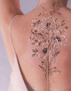 the back of a woman's body with flowers tattooed on her upper and lower back