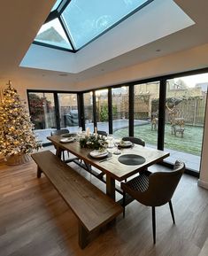 a dining room table with two chairs and a bench in front of the glass windows