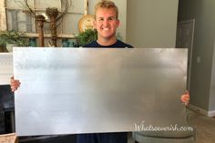 a man holding up a metal sign in his living room