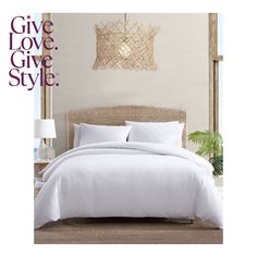 a bed with white comforter and pillows in a bedroom next to a wall hanging