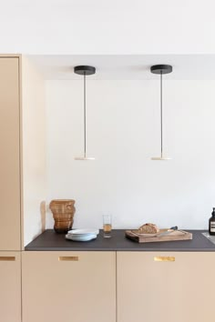 a kitchen with white walls and black counter tops, two hanging lights above the cabinets