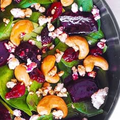 a salad with beets, walnuts and spinach leaves in a black bowl