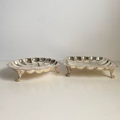 two silver dishes sitting next to each other on a table