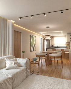 a living room filled with furniture next to a kitchen and dining room table on top of a hard wood floor