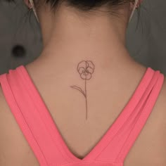 a woman's back neck with a small flower tattoo on her left side ribcage