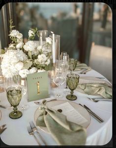 the table is set with white flowers and silverware