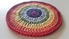 a multicolored crocheted coaster sits on a white surface