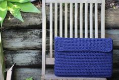 a blue crocheted blanket sitting on top of a wooden chair next to a potted plant