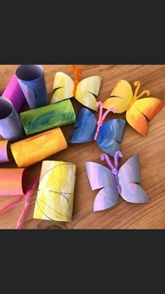 several different colored paper butterflies on a wooden table