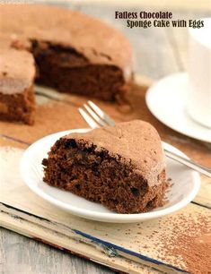 a piece of chocolate cake on a white plate with a fork next to the slice