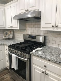 a stove top oven sitting inside of a kitchen next to white cabinets and counter tops