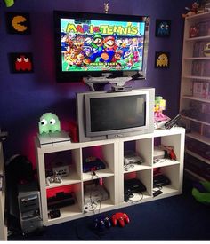 a room with a tv, video game console and shelves filled with gaming accessories in front of it