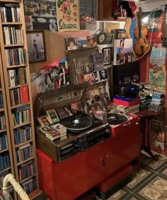 a record player sitting on top of a red cabinet in a room filled with books