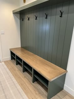 an empty bench in the middle of a room with two coat racks on each side