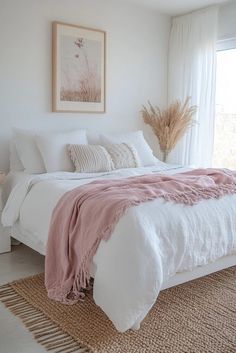 a white bed with pink blankets and pillows