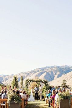 a couple getting married at their wedding ceremony in front of the mountain range with mountains behind them