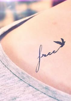 a small tattoo on the back of a woman's shoulder that reads, free