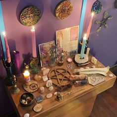 a wooden table topped with lots of different types of items next to candles and pictures