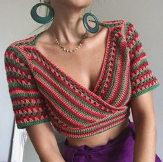 a woman with large hoop earrings wearing a red, green and pink crochet top