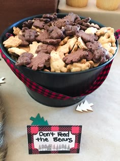 a bowl filled with cookies next to a sign and cupcakes on the table